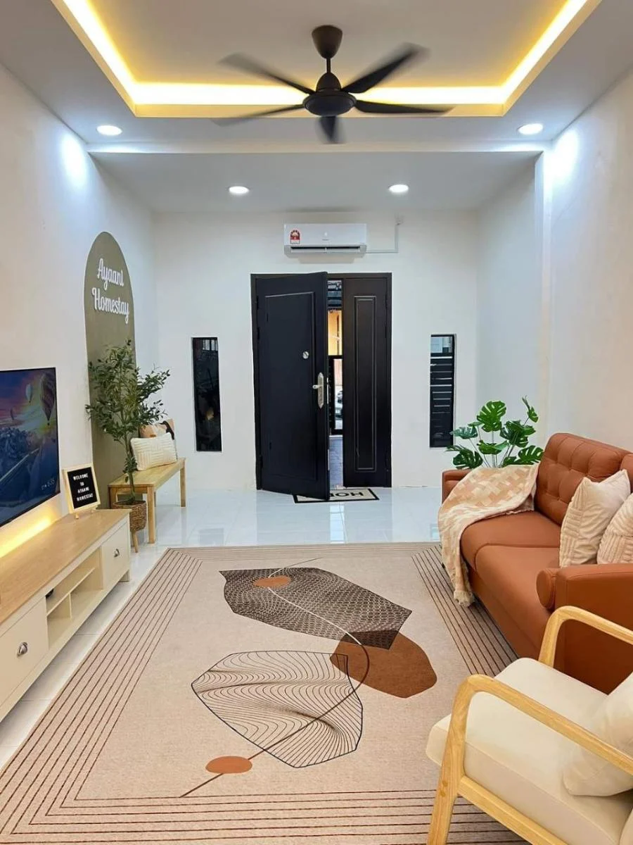 Ruang tamu Ayaani Homestay di Melang, Kuala Pilah dengan sofa terracotta, TV dan papan nama Ayaani Homestay